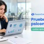 Reclutadora revisa en su laptop los resultados de pruebas psicométricas de un candidato
